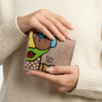 Hand-painted beige leather wallet with cubist abstract portrait, green cheek, and white polka dots. Signed by Rime Sbai.