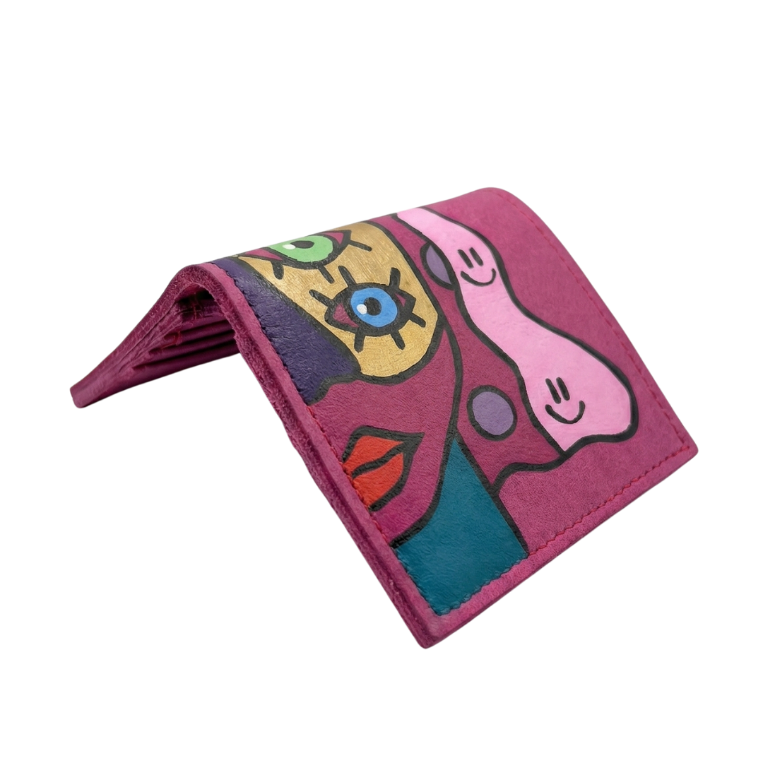 Hand-painted pink leather wallet with cubist abstract portrait, green cheek, and white polka dots. Signed by Rime Sbai.