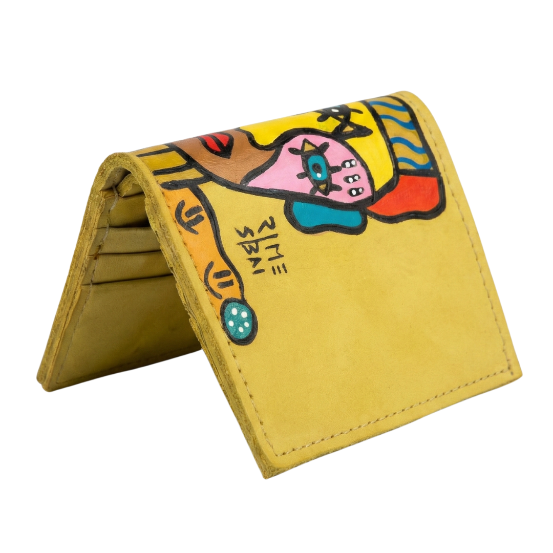 Hand-painted yellow leather wallet with cubist abstract portrait, green cheek, and white polka dots. Signed by Rime Sbai.