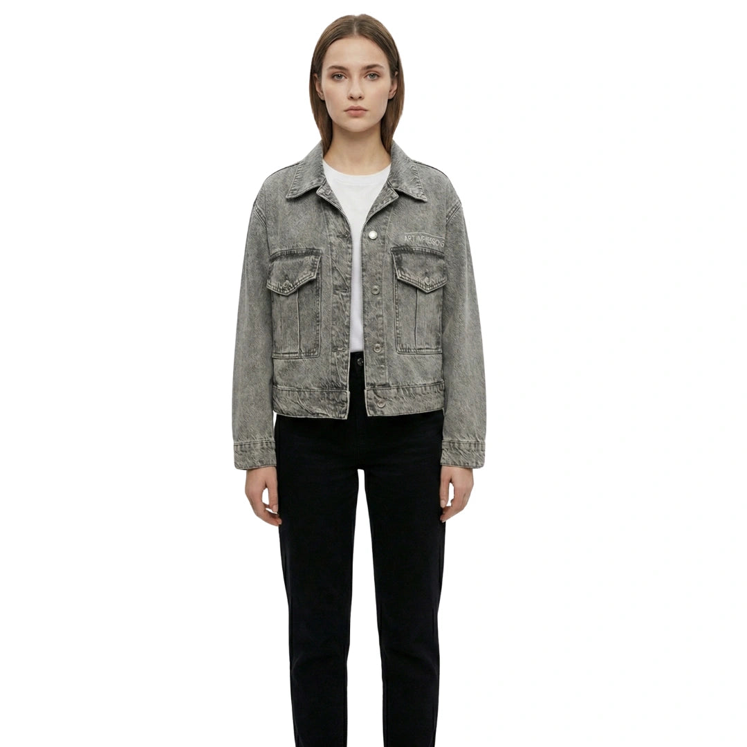 Front view of a woman wearing the grey boxy trucker denim jacket with Artgressions logo detail.